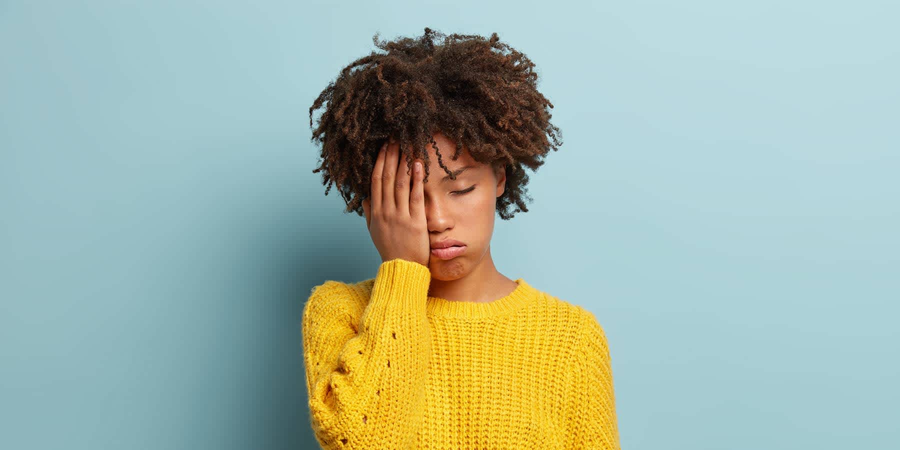 Young woman with sleepy face in her hand and wondering why she is tired all the time