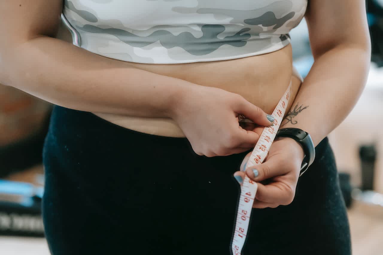 Woman measuring waist while wondering about BMI and weight management