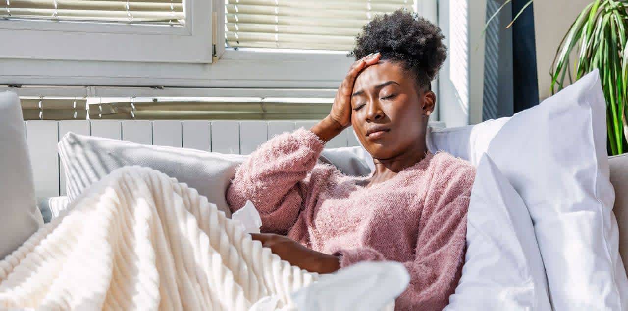 Young woman with blanket and pillows experiencing insomnia due to allergies