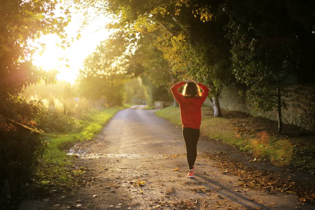 Woman walking down trail filled with sunlight to highlight vitamin D, the "sunshine vitamin"