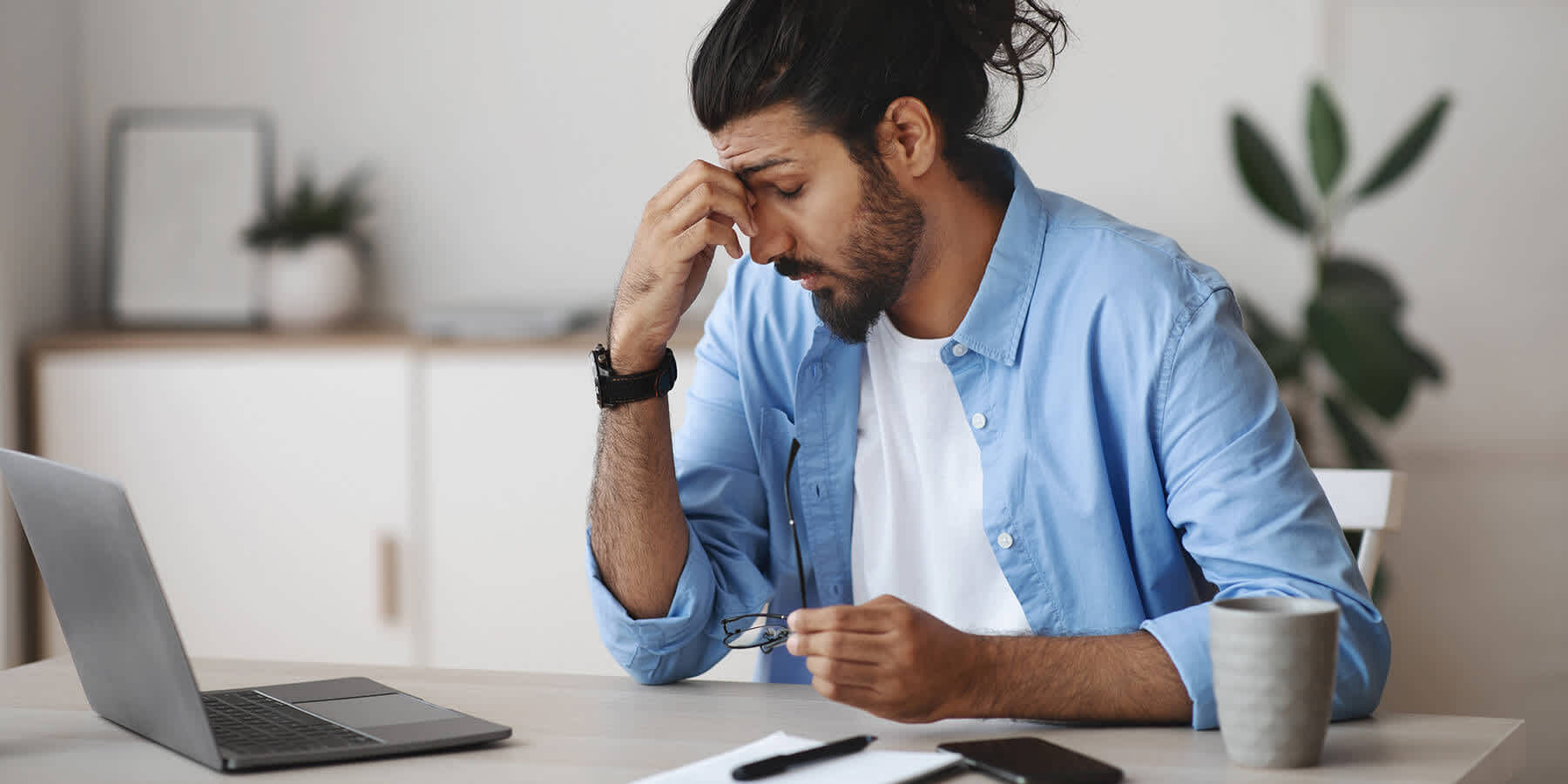 Man in blue shirt using laptop to learn whether low testosterone causes ED