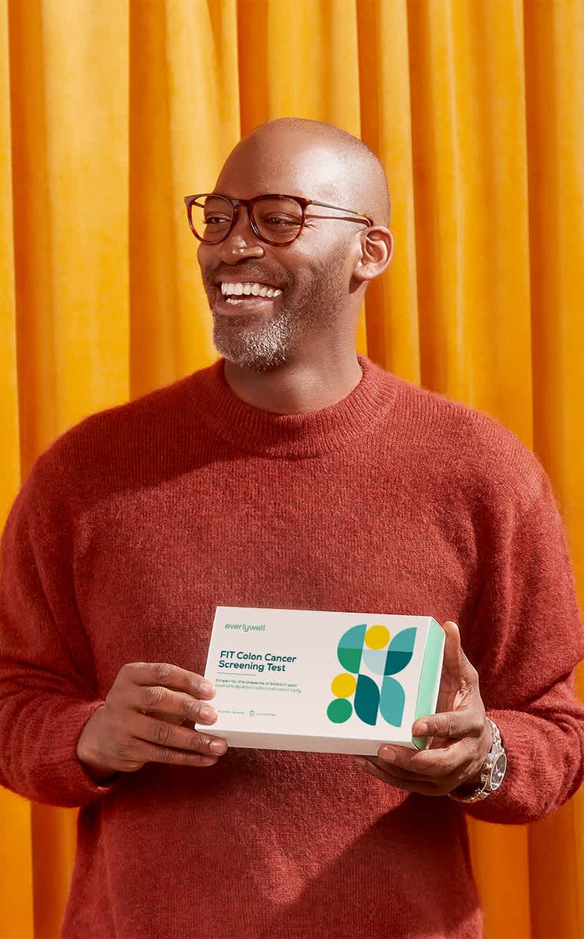 Man smiling and holding Everlywell FIT Colon Cancer test