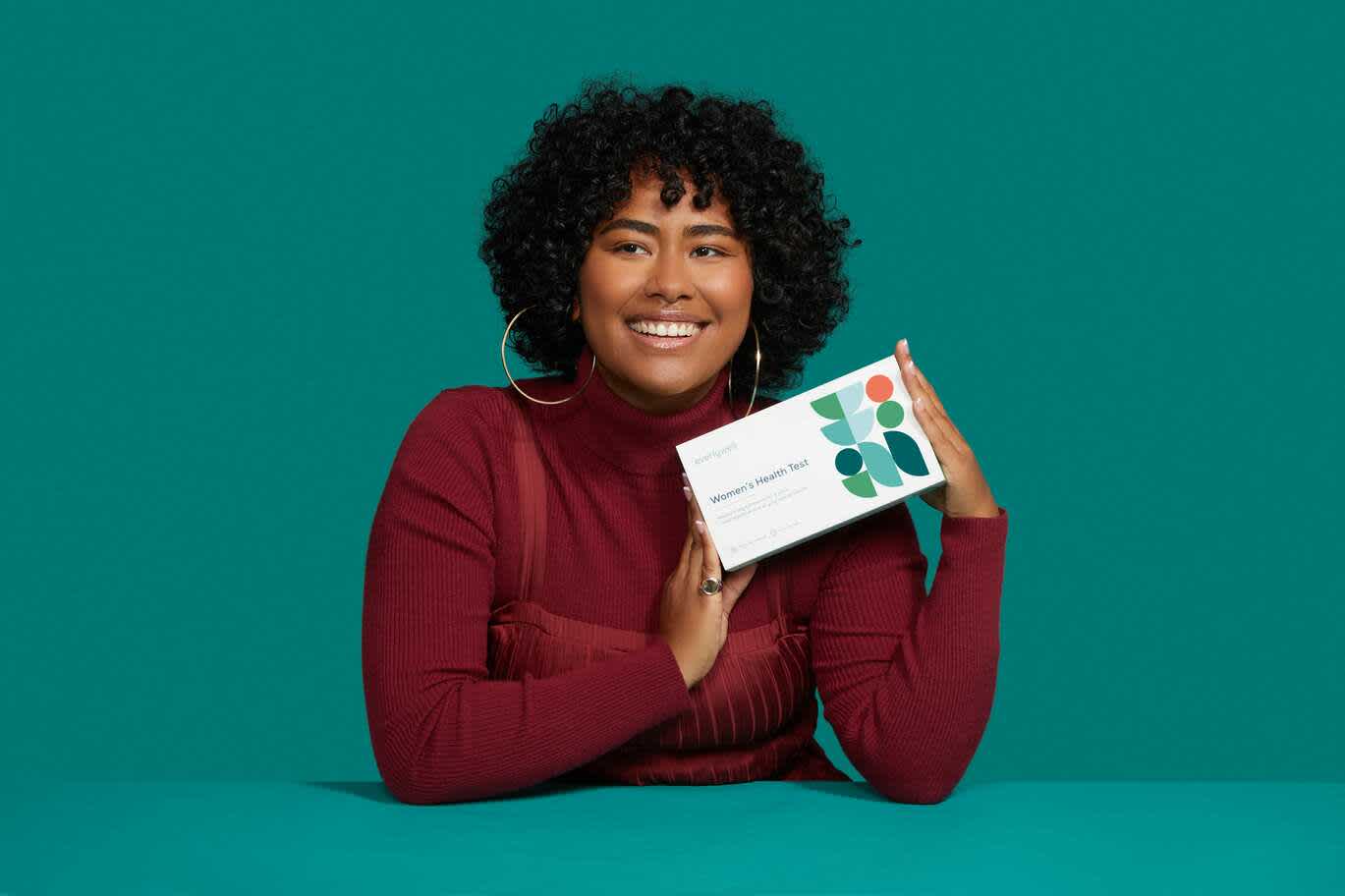 Smiling woman holding Everlywell Women’s Health Test