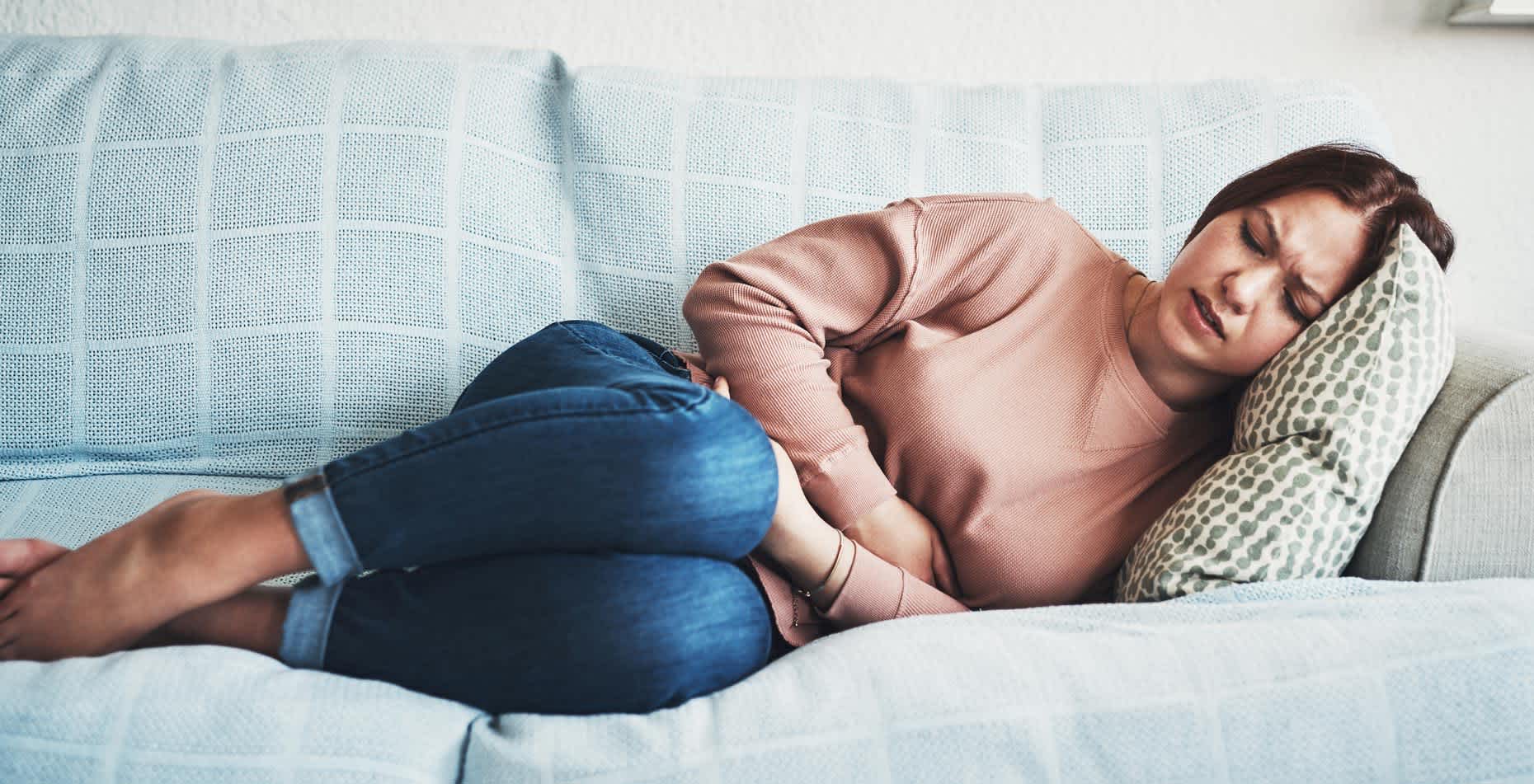 Woman lying sideways experiencing stomach pains