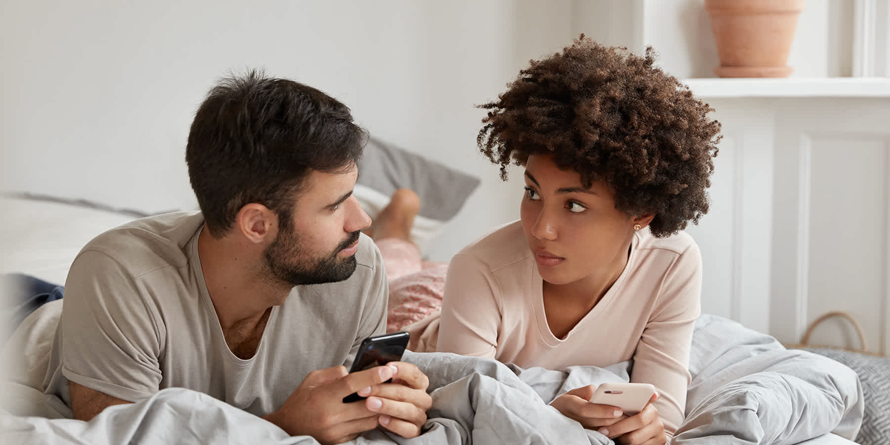 Couple in bed looking up how common syphilis is on smartphone