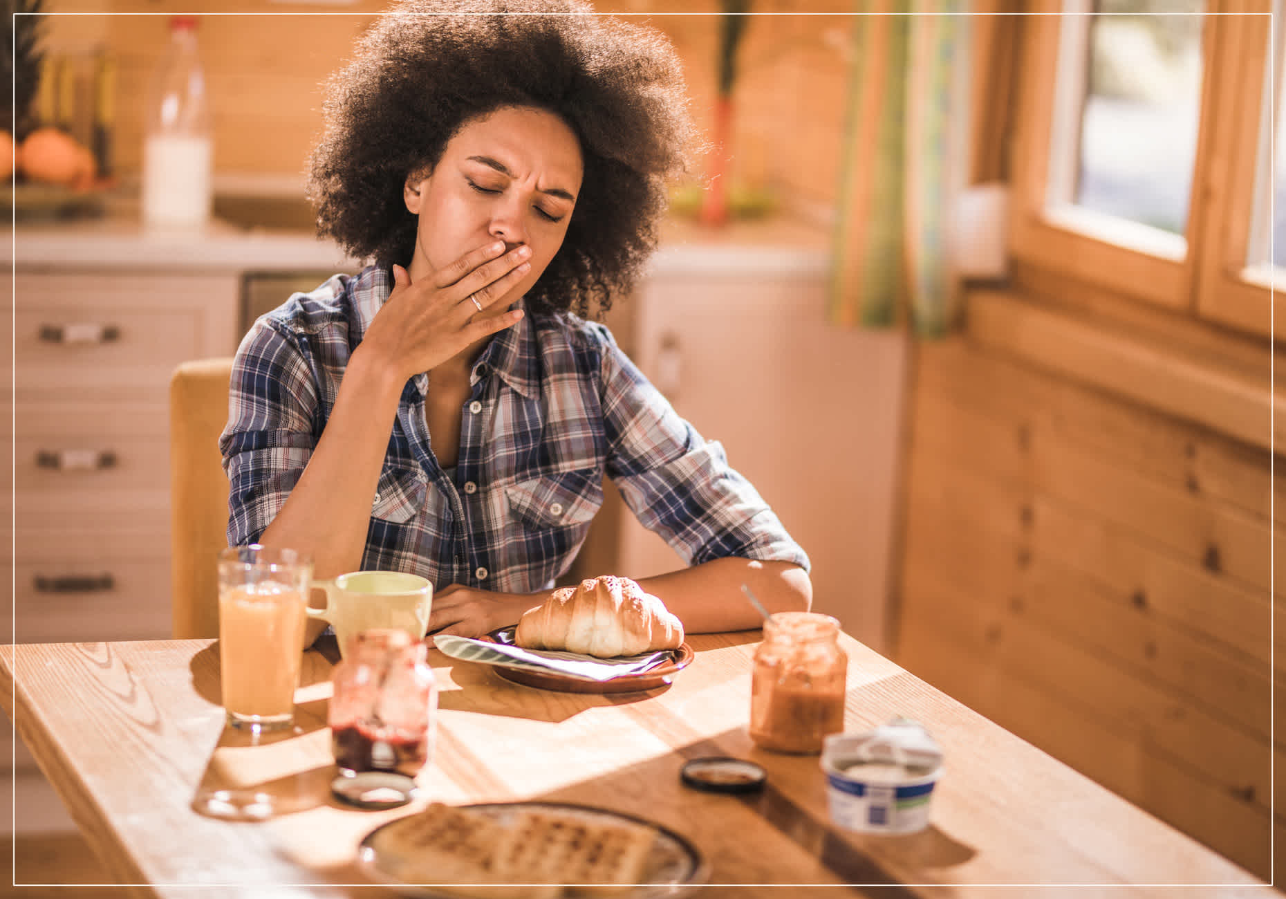 Woman sitting at table and yawning while wondering how to speed up digestion