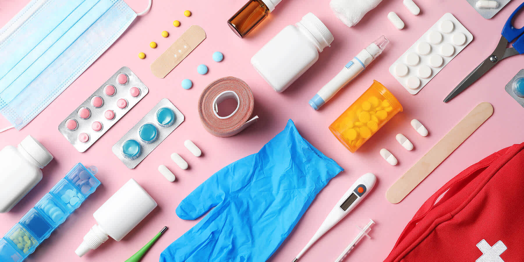 A variety of health items, including bandages, medicines, and more against a pink background