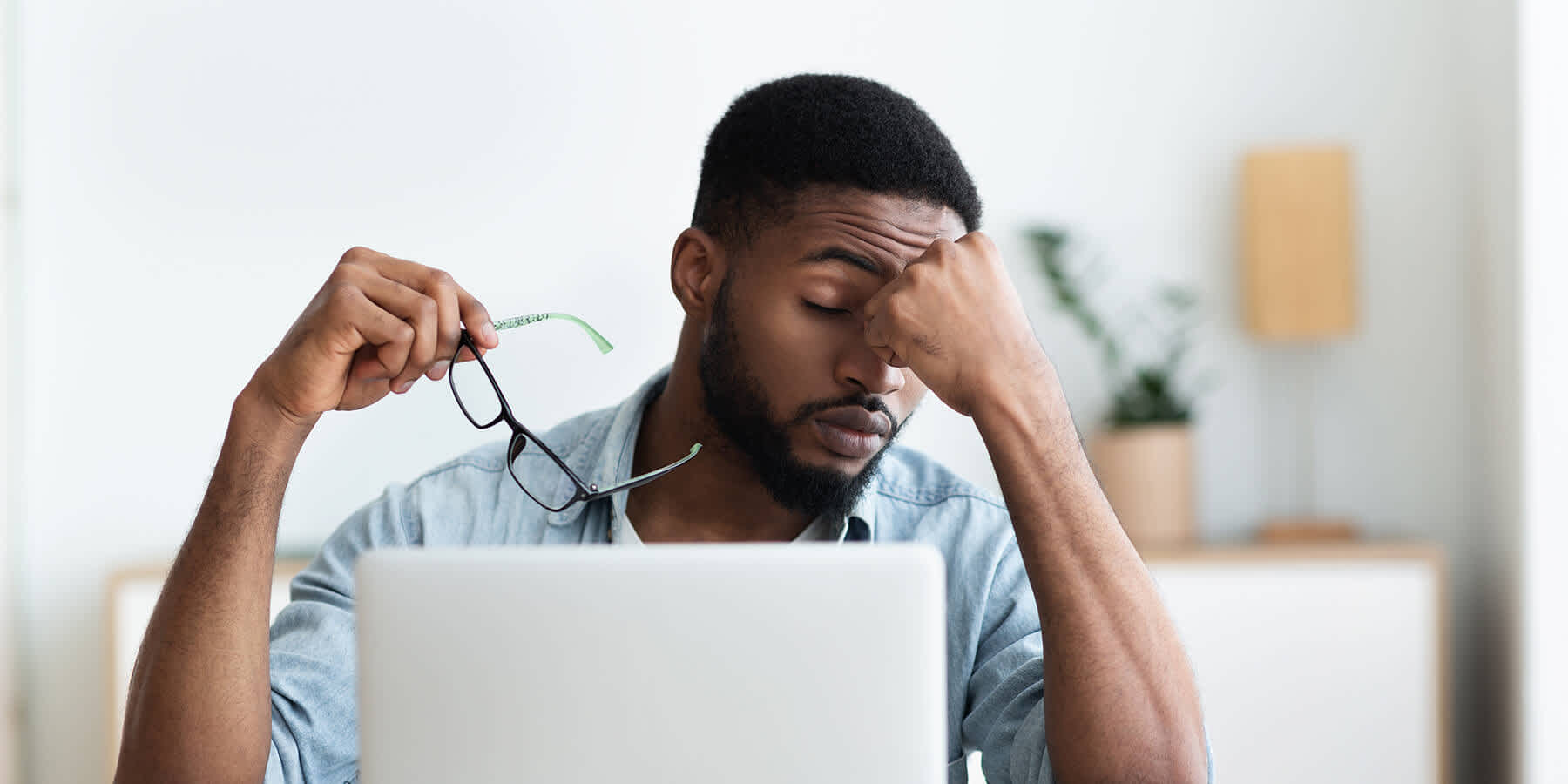 Man with laptop computer looking tired while looking up signs of too much vitamin D