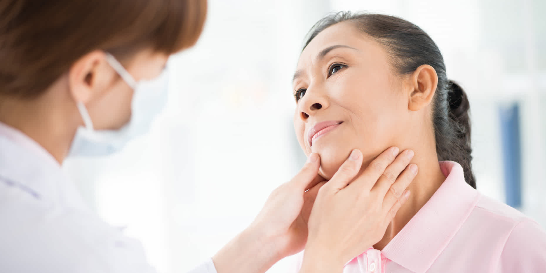 Healthcare provider examining a woman's neck for possible thyroid issues