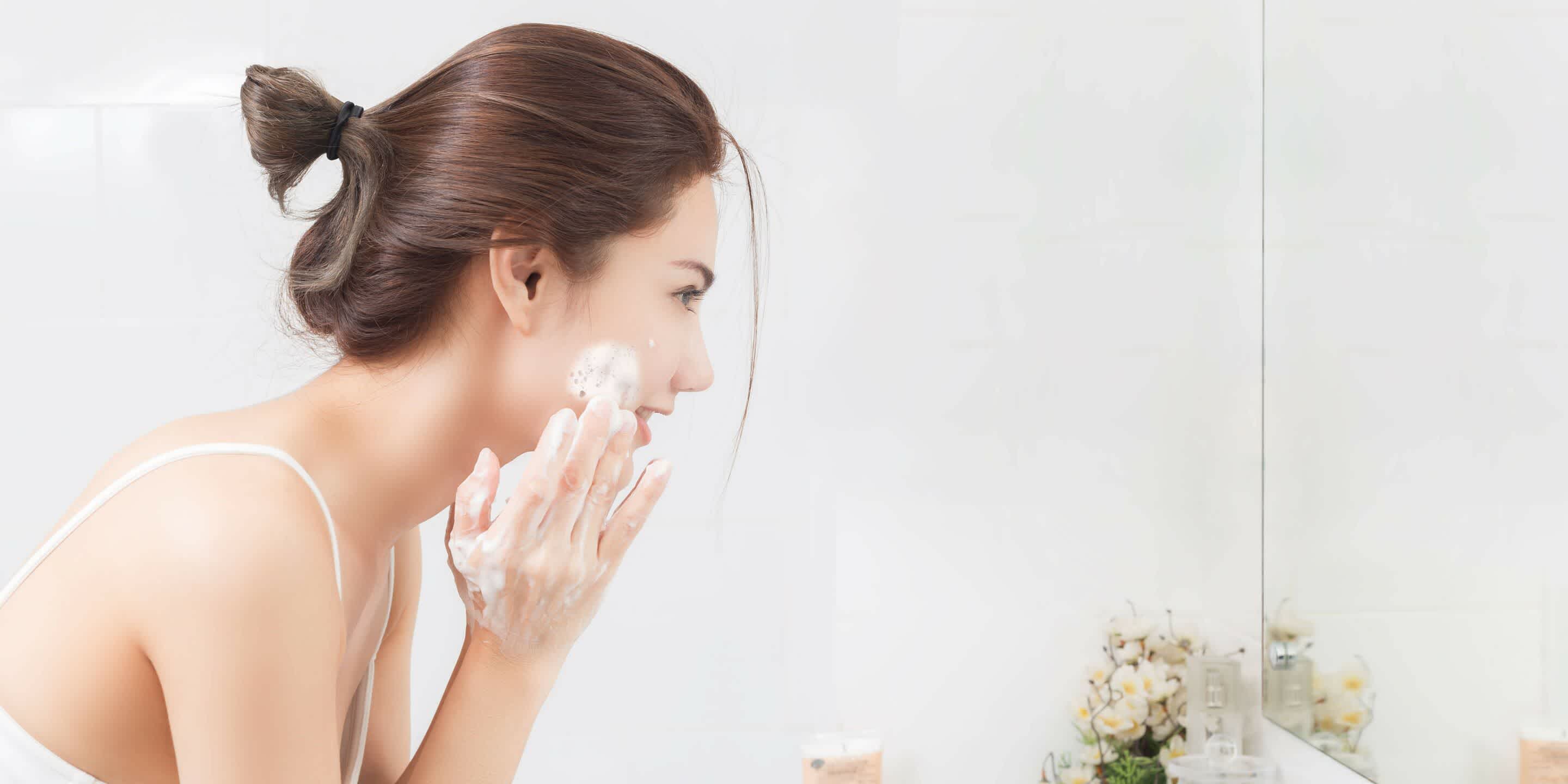 Young woman washing face after understanding acne