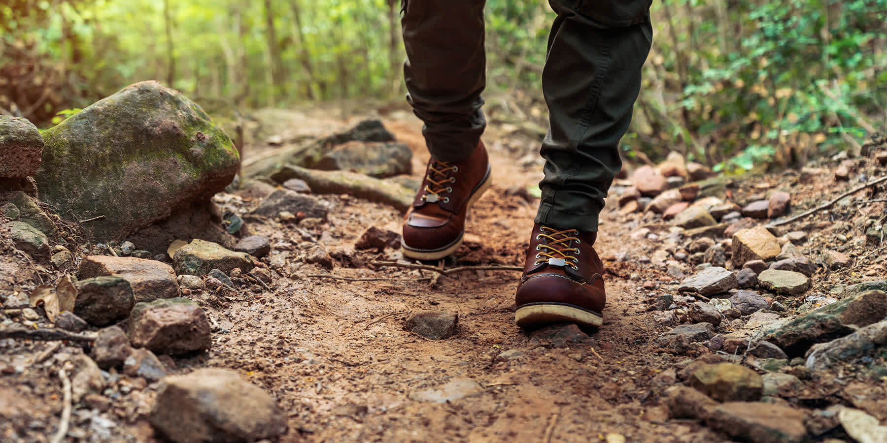 Person walking on forest trail with pants and boots to help prevent bite from tick with Lyme disease