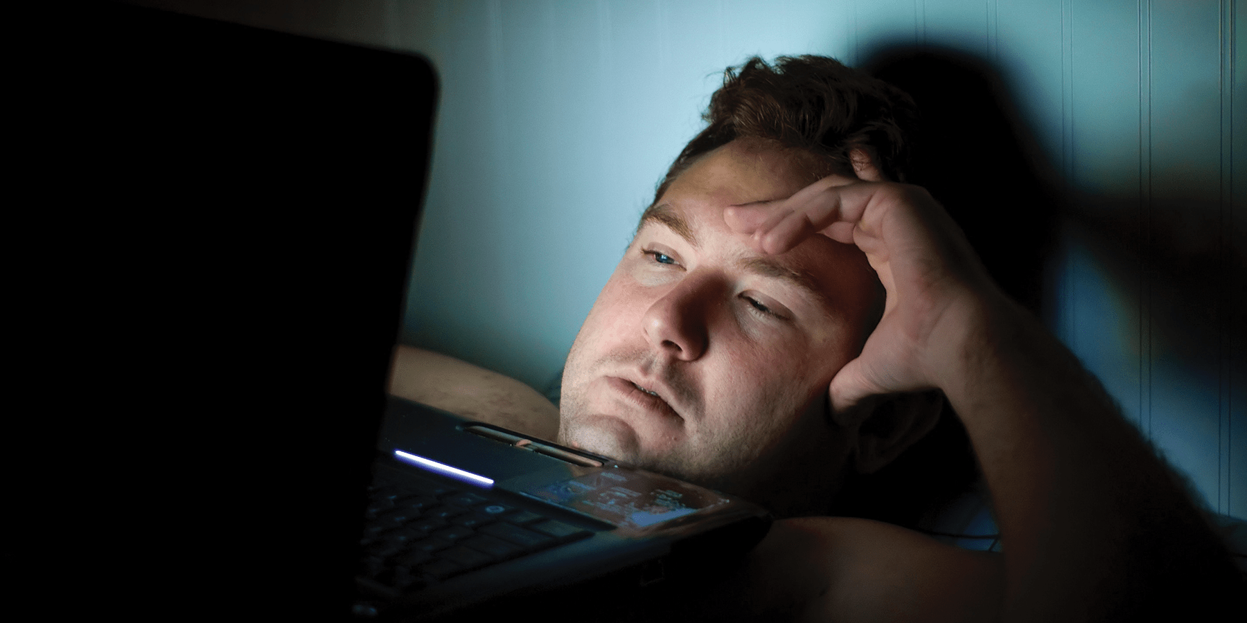 Man staying up late on computer and experiencing sleep loss